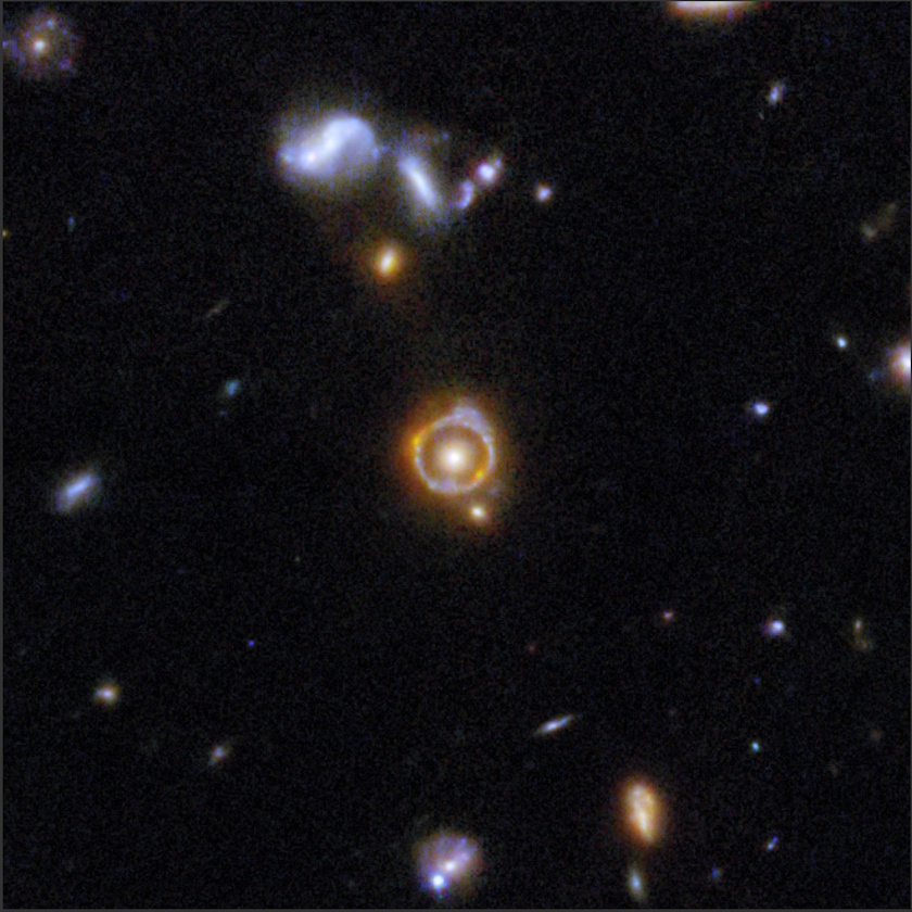 A group of galaxies in deep space, imaged by COSMOS-Web JWST, displays a prominent orange glowing ring—likely a gravitational lens—around a central object, surrounded by numerous faint stars and galaxies on a dark background.