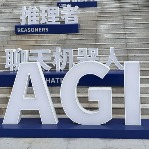 Large white letters spelling "AGI" are displayed on a platform in front of steps, with additional bilingual signs reading "REASONERS" and "CHATBOTS" in English and Chinese.